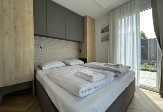 Chambre moderne du chalet Domus 4 à Zilverstrand, Belgique, avec lit double et grande baie vitrée.