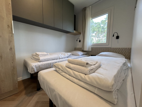Slaapkamer in chalet Domus 4 op Zilverstrand, België, met drie eenpersoonsbedden en moderne inrichting.