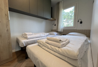 Chambre du chalet Domus 4 à Zilverstrand, Belgique, avec trois lits simples et une décoration moderne.