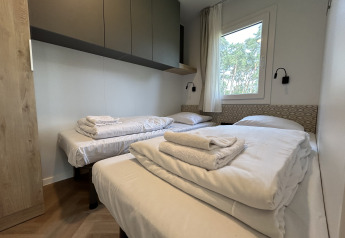 Slaapkamer in chalet Domus 4 op Zilverstrand, België, met drie eenpersoonsbedden en moderne inrichting.