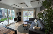 Salon moderne du lodge Belsano 6 à Zilverstrand, Belgique, avec de grandes fenêtres et une décoration contemporaine.