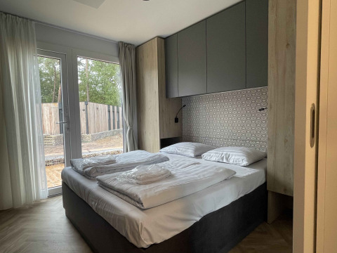 Modern lodge slaapkamer in Belsano 6 bij Zilverstrand in België met tweepersoonsbed en grote ramen.