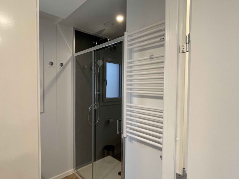 Moderne badkamer met douche, raam en handdoekradiator in lodge Belsano 6 op Zilverstrand, België.
