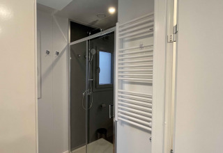 Moderne badkamer met douche, raam en handdoekdroger in Belsano 6 lodge te Zilverstrand, België.