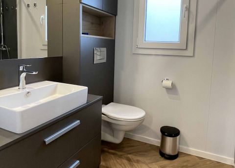 Moderne badkamer in Belsano 6, Zilverstrand in België met hangtoilet, wastafel en raam.