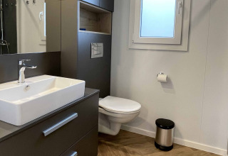 Moderne badkamer in Belsano 6, Zilverstrand te België met zwevend toilet, wastafel en raam.