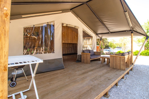 Tienda safari con terraza de madera, cómodos sofás, barbacoa y aire acondicionado para relajarse.
