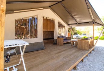 Tenda safari con veranda in legno, divani comodi, barbecue e aria condizionata, immersione nella natura.