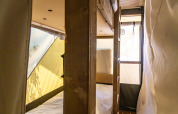 Interno di una tenda safari con letti a castello in legno, pavimento in legno e pareti di tela illuminate.