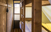 Interior view of a safari tent’s sleeping area with wooden bunk beds and natural light shining in.