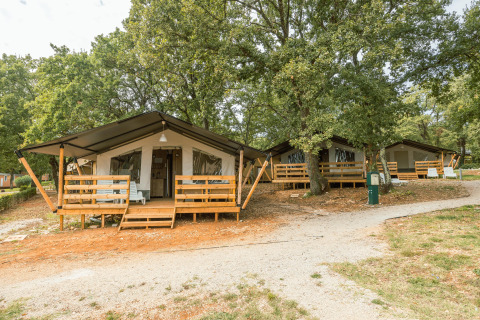 Tienda safari con baño privado y aire acondicionado en Camping Valkanela, Croacia, rodeada de árboles.