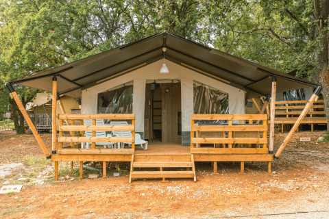 Tenda safari con veranda, aria condizionata e servizi igienici privati al Camping Valkanela, Croazia, tra gli alberi.