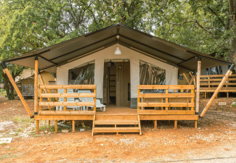 Tenda safari con veranda, aria condizionata e servizi igienici privati al Camping Valkanela, Croazia, tra gli alberi.