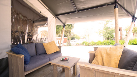 Safari tent with private sanitary facilities and air conditioning, cozy seating with pillows.