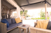 Tenda safari con servizi igienici privati e aria condizionata, area relax con cuscini colorati.