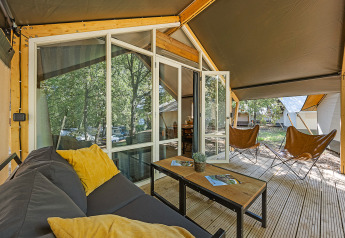 Veranda della tenda safari Bella Vista con divano e sedie al Camping Porto Sole, Croazia, immersa nel verde.