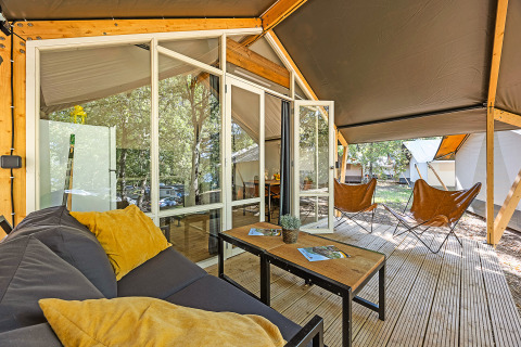 Safari tent Bella Vista with air conditioning, outdoor deck, wooden furniture, and relaxing forest view.