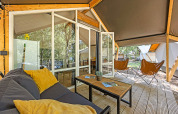 Tenda safari Bella Vista con aria condizionata, veranda in legno, sedie confortevoli e vista sul verde.
