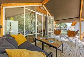 Tenda safari Bella Vista con aria condizionata, veranda in legno, sedie confortevoli e vista sul verde.
