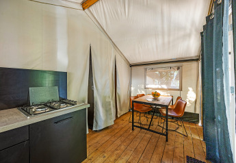 Vista interna della tenda Safari Bella Vista con cucina, tavolo da pranzo e sedie al Camping Porto Sole in Croazia.