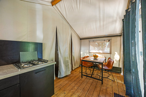 Vista interna della tenda Safari Bella Vista con cucina, tavolo da pranzo e sedie al Camping Porto Sole in Croazia.