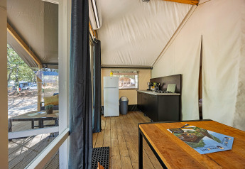 Vista interna della tenda Safari Bella Vista con aria condizionata al Camping Porto Sole in Croazia, con cucina e zona pranzo.