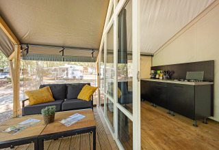 Tienda Safari Bella Vista con aire acondicionado, sofá cómodo, cocina y terraza con vistas al camping.