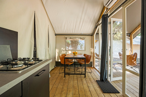 Innenraum des Safari-Zeltes Bella Vista mit Klimaanlage, Küche, Esstisch und Terrasse im Freien.