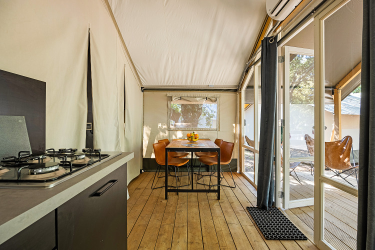 Innenraum des Safari-Zeltes Bella Vista mit Klimaanlage, Küche, Esstisch und Terrasse im Freien.