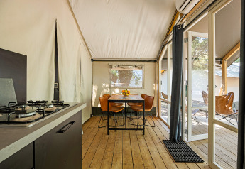 Indretning af Safari telt Bella Vista med aircondition, køkken, spisebord og udsigt til terrassen.