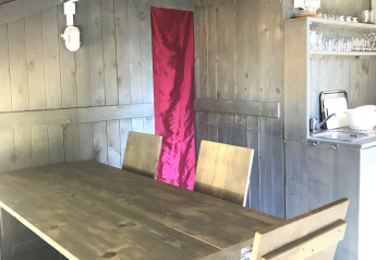 Indvendigt billede af et safari telt med træbord, stole, aircondition og tekøkken på Camping Valkanela.