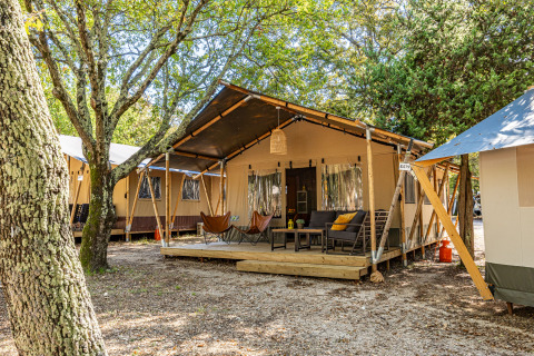 Safari-Zelt-Lodge mit Klimaanlage, gemütlicher Terrasse und Sitzgelegenheiten im naturreichen Umfeld.