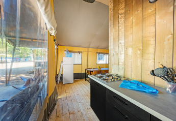 Vista interna di una tenda Safari Lodge con aria condizionata, cucina, tavolo da pranzo e frigorifero.