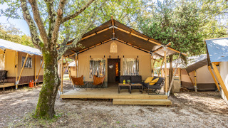 Tente safari Lodge climatisée au Camping Lanterna en Croatie, salon extérieur confortable sous les arbres.