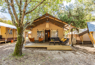 Safari tent Lodge with air conditioning at Camping Lanterna in Croatia, cozy outdoor seating under trees.
