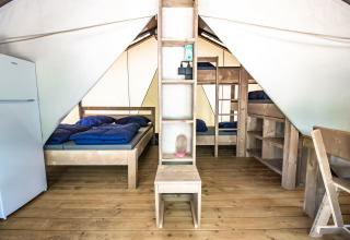 Interno della Safari Tent Comfort con pavimento in legno, letto matrimoniale, letti a castello e frigo.