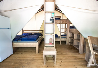 Interno della Safari Tent Comfort con pavimento in legno, letto matrimoniale, letti a castello e frigo.