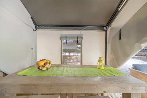Vista interna della Safari Tent Comfort al Camping Porto Sole in Croazia con tavolo di legno e fruttiera.
