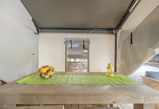 Innenaufnahme des Safari Tent Comfort auf Camping Porto Sole in Kroatien mit Holztisch und Obstschale.