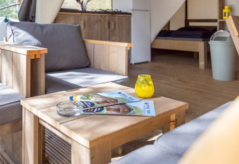 Indretning af Safari Tent Comfort på Camping Porto Sole i Kroatien med træmøbler og sofaer.