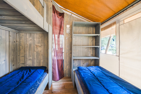 Binnenkant van Safari Tent Luxury op Camping Valkanela in Kroatië met twee bedden en open rekken.