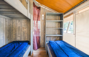 Indretning af Safari Tent Luxury ved Camping Valkanela i Kroatien med to senge og åbne hylder.