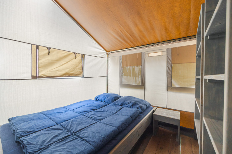 Vue intérieure de Safari Tent Luxury avec lit double, table de nuit et étagère au Camping Valkanela en Croatie.