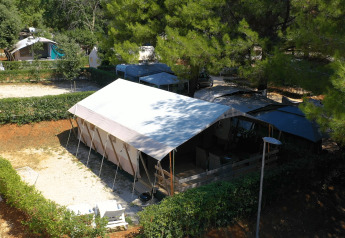 Safari Tent Luxury al Camping Valkanela in Croazia, circondata da alberi e siepi in un ambiente tranquillo.