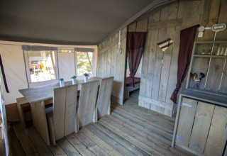 Interior de la Safari Tent Luxury en Camping Valkanela, Croacia, con mobiliario de madera y ambiente rústico.