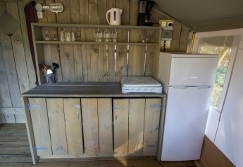 Kitchen area in Safari Tent Luxury at Camping Valkanela, Croatia, with stove, fridge, and wooden cabinets.