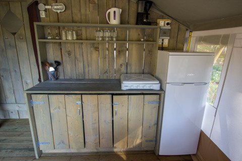 Cocina en tienda Safari Luxury de Camping Valkanela, Croacia, con estufa, nevera y gabinetes de madera.