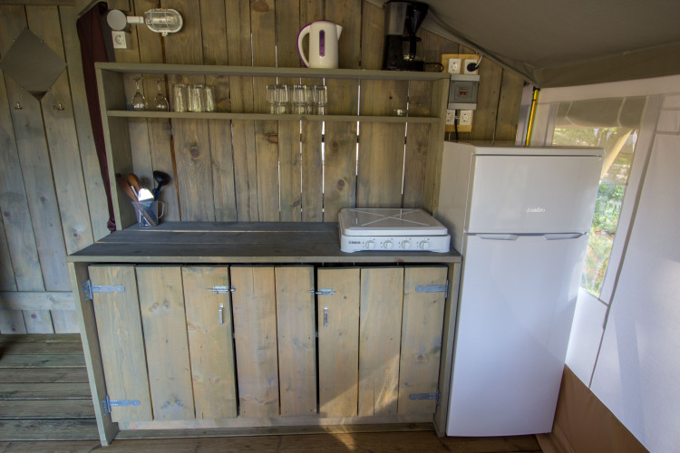 Cocina en tienda Safari Luxury de Camping Valkanela, Croacia, con estufa, nevera y gabinetes de madera.