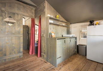 Vista interior de la Safari Tent Luxury en Camping Lanterna, Croacia, con cocina y paredes de madera.