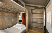 Vista interna della Safari Tent Luxury con letto a castello e scaffali in legno al Camping Lanterna, Croazia.